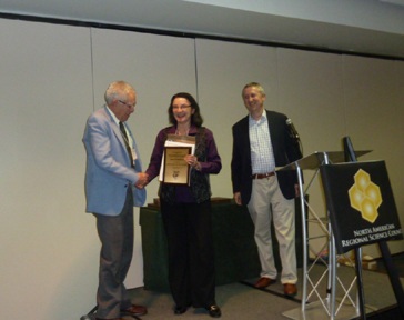 Janet Kohlhase (center) receiving a plaque from David Boyce and Gilles Duranton